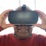 Glimlachende oudere man draagt een VR-bril en beleeft een virtuele ervaring